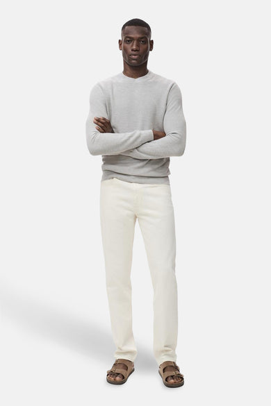 Sweat-shirt gris avec col rond de MANGO, porté avec des jeans beiges et des sandales brunes.