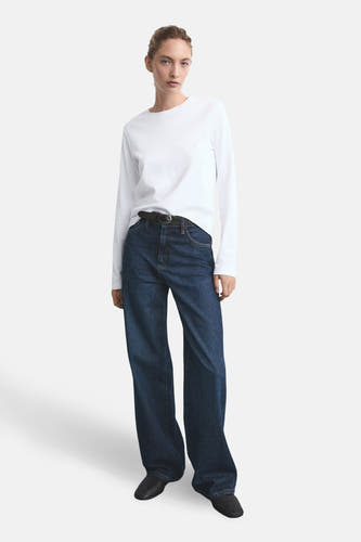 Jean large de denim bleu foncé de MANGO, porté avec un t-shirt blanc et une ceinture noire.