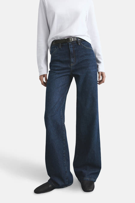 Jean bleu marine large de MANGO, porté avec une ceinture noire et des chaussures noires, associé à un t-shirt blanc.