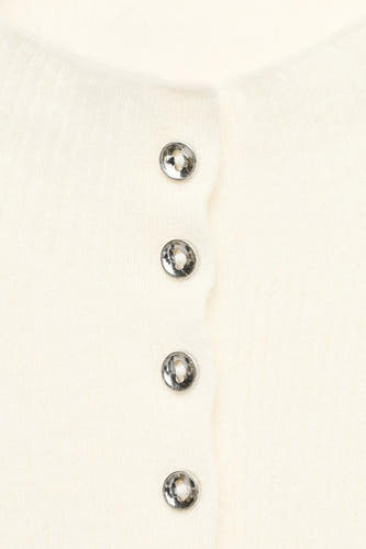 Gilet beige de MANGO avec des boutons argentés sur une courte, close-up.