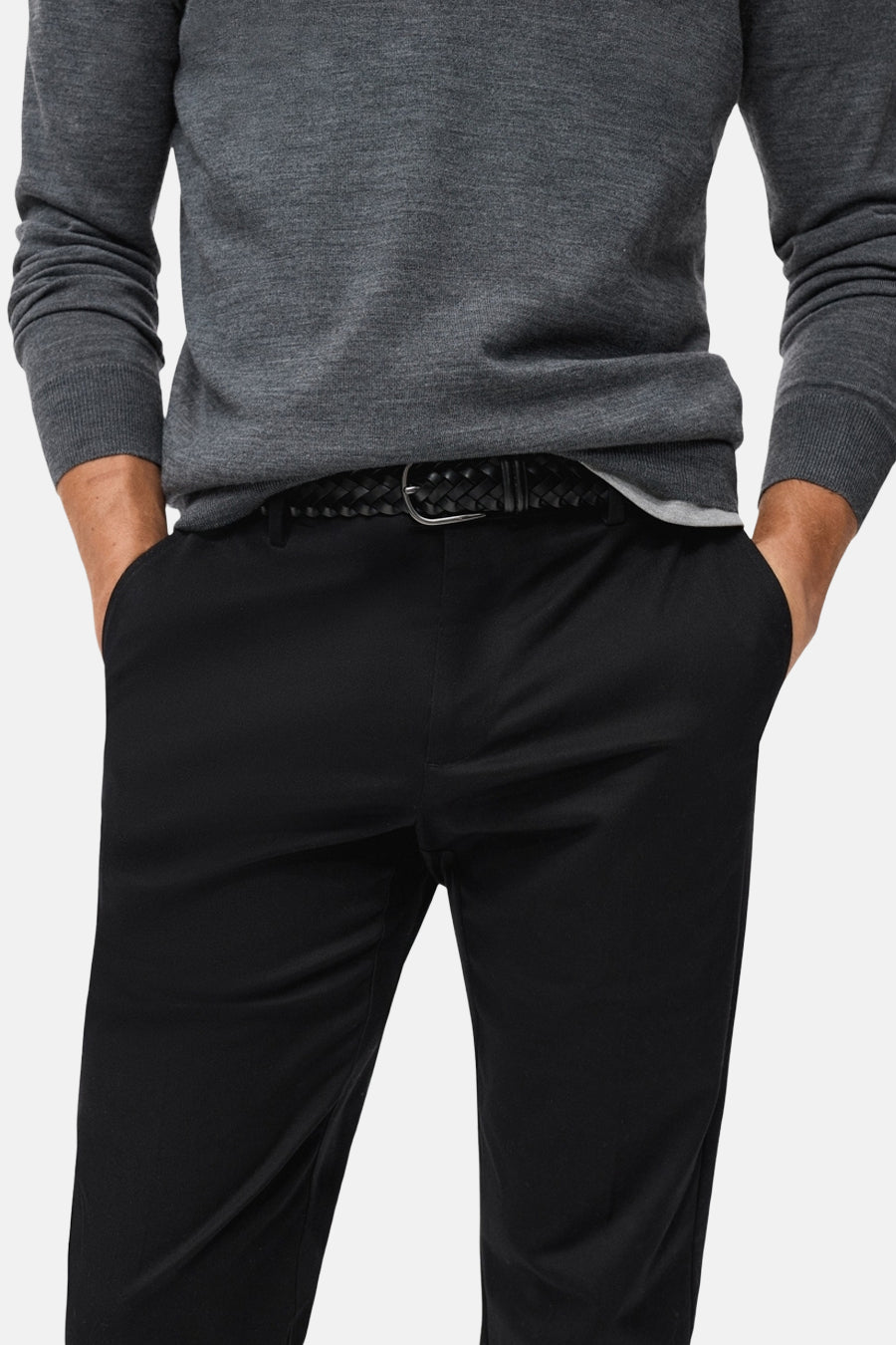 Pantalon bleu marine de MANGO, avec une ceinture tressée noire, et les mains dans les poches.