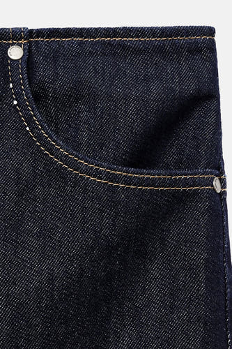 Jupe en denim bleu marine de MANGO, avec une poche brodée et des points contrastants, gros plan.