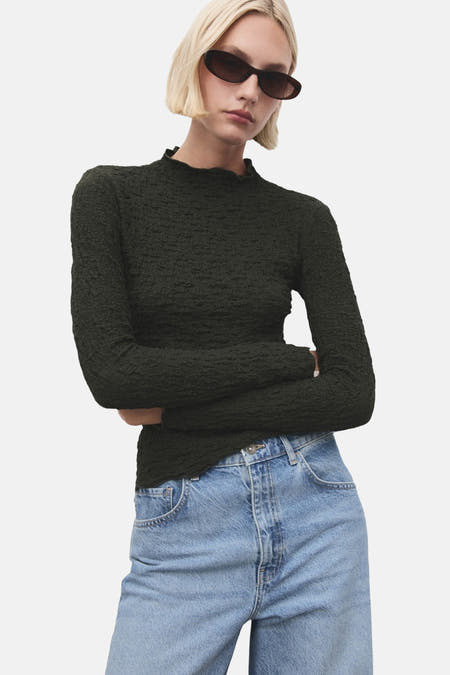 T-shirt kaki à manches longues de MANGO, avec une texture froissée, associé à un jean bleu, vue arrière.