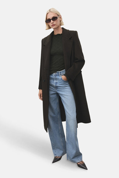 Khaki T-shirt met lange mouwen van MANGO, gedragen met een lange jas en wijde jeans.