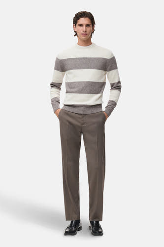 Multikleurige trui met ronde hals van MANGO, met brede horizontale strepen en gecombineerd met een bruine pantalon en zwarte loafers.

