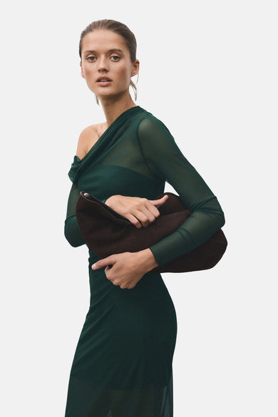 Groene jurk met lange mouwen van MANGO, met gedrapeerd detail en clutch in de hand.
