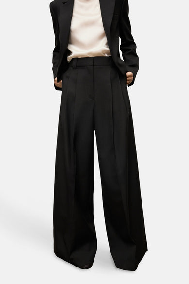 Pantalon de costume noir MANGO, vu de l'arrière avec des largees et un chemisier court coordonné.