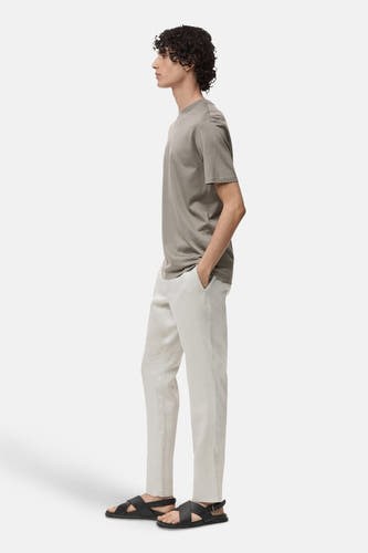 T-shirt gris à manches courtes de MANGO, porté avec un short en lin léger et des sandales noires, en vue latérale.