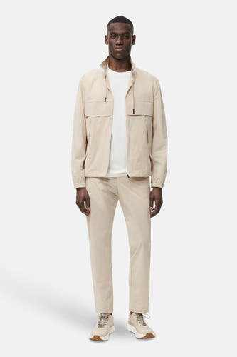 Beige, manteau court de MANGO, avec une col montant, des poches et porté sur un T-shirt blanc.