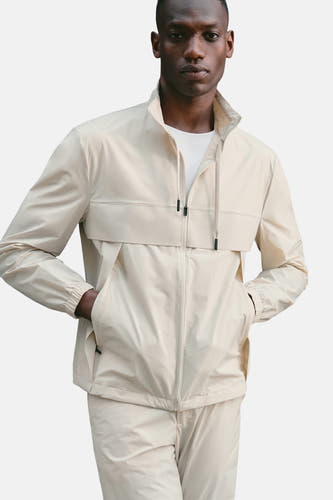 Manteau court beige de MANGO, avec un col montant et des détails d'une fermeture éclair.