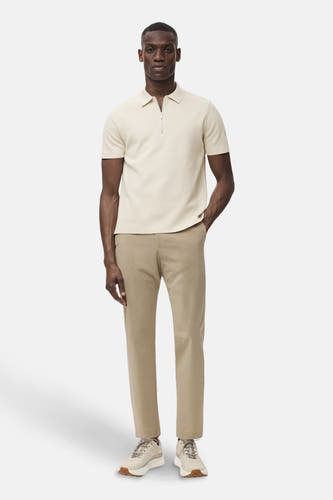 Pantalon beige de MANGO, associé à une polo claire et des sneakers coordonnées.