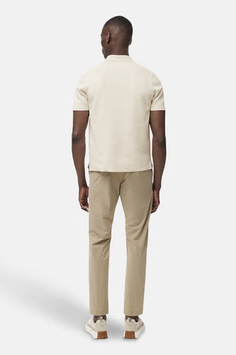 Pantalon beige de MANGO, vu de de l'arrière, combiné avec un polo crème et des baskets basses.
