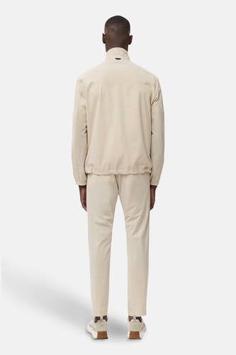 Pantalon écru de MANGO, vu de derrière, avec une veste coordonnée et des baskets blanches.