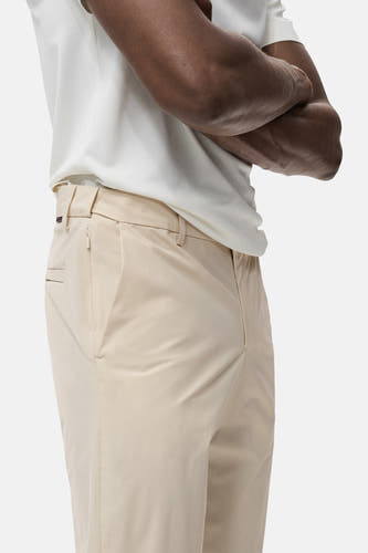 Pantalon écru de MANGO, avec poche latérale et plis subtils, associé à une chemise blanche.