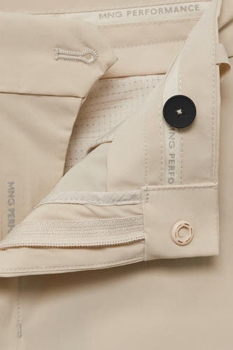 Pantalon écru de MANGO Performance avec une fermeture à bouton et un détail de zip.