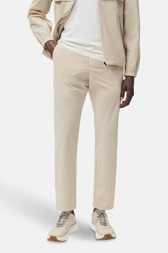 Pantalon écru de MANGO, porté avec un t-shirt blanc et une veste beige, et des chaussures coordonnées.