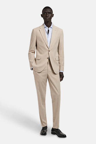 Pantalon costum beige de MANGO, combinado con una camisa azul claro y zapatos negros.