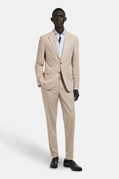 Pantalon costum beige de MANGO, combinado con una camisa azul claro y zapatos negros.