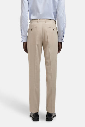 Pantalon de costume beige MANGO, avec des poches à l'arrière, porté avec un chemisier bleu clair et des chaussures noires.