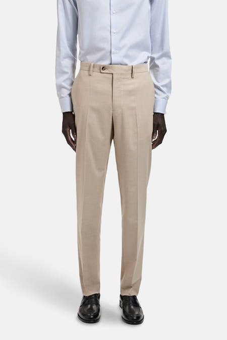 Pantalon de costume beige MANGO, avec poches et fermeture à bouton, associé à une chemise bleu clair et des chaussures noires.