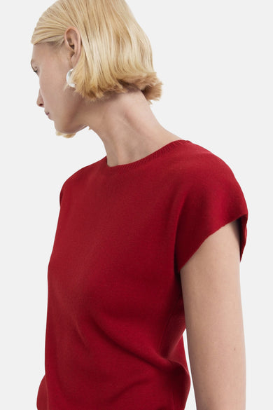T-shirt sans manches rouge de MANGO, sur un modèle avec des boucles d'oreilles argentées, en vue latérale.