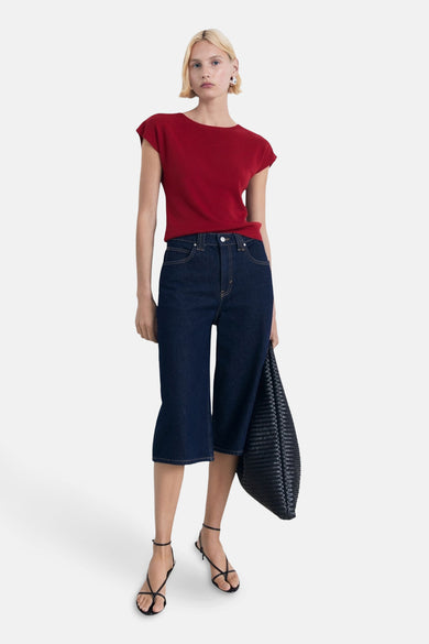 T-shirt sans manches rouge de MANGO, associé à des culottes en denim foncé et des sandales noires, plus une sac noire.