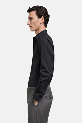 Chemise noire à manches longues de MANGO, avec un pantalon gris, en vue latérale.