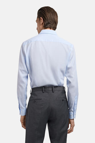 Chemise bleue à manches longues de MANGO, vue de derrière, avec un pantalon gris.