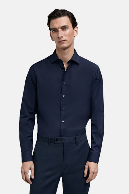 Chemise bleue à manches longues de MANGO, portée avec un pantalon foncé.