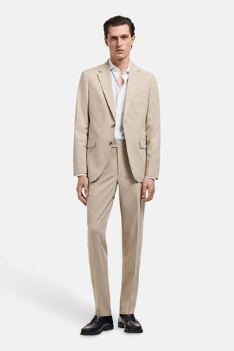 Chemise blanche à manches longues de MANGO, portée sous un manteau beige et associée à des chaussures noires.