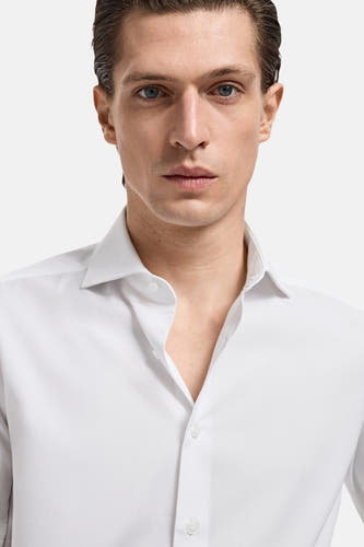 Chemise blanche à manches longues de MANGO, portée par un homme avec une encolure ouverte.
