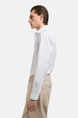 Chemise blanche à manches longues de MANGO, vue en profil avec un pantalon beige.