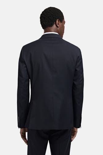 Blazer bleu de MANGO, vu d' dosrière, avec une taille subtile et des détails de boutons sur les manches.