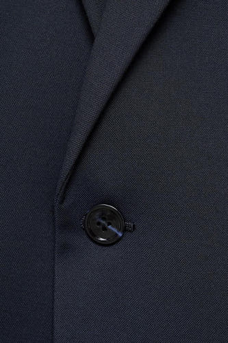 Blazer bleu de MANGO, avec un nœud noir et une subtile texture.