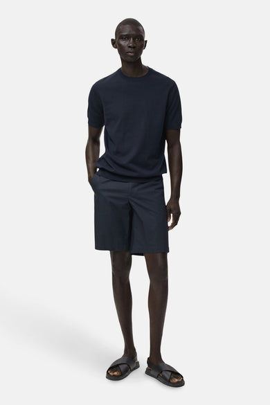 T-shirt bleu à manches courtes de MANGO, porté avec des shorts et des sandales en cuir.