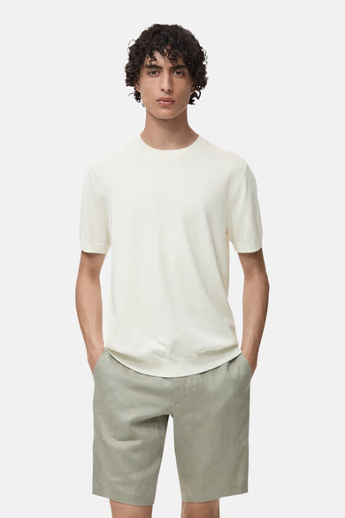 T-shirt écru à manches courtes de MANGO, avec cheveux bouclés et short vert.