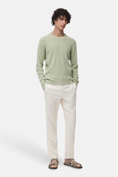 T-shirt vert avec col rond de MANGO, à longues manches, porté avec un short en lin léger et des sandales.