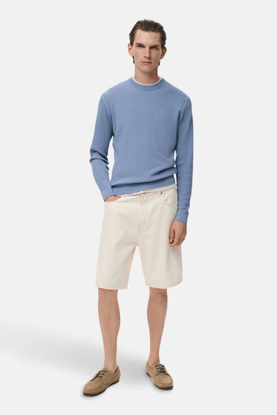 T-shirt bleu avec col rond de MANGO, associé à des shorts écru et des mocassins en cuir suédé.