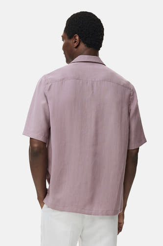 Chemise bleue à manches courtes de MANGO, vue de derrière avec un short blanc.