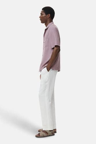 Chemise bleue à manches courtes de MANGO, portée avec un short blanc et des sandales croisées, en vue latérale.