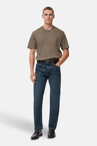 T-shirt kaki à manches courtes de MANGO, porté avec un jeans bleu marine et des chaussures en cuir noires.