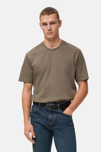 T-shirt kaki à manches courtes de MANGO, associé à un jean bleu et une ceinture tressée.