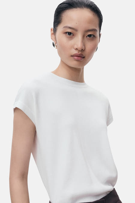 T-shirt sans manches de MANGO, avec des manches retroussées et porté avec des boucles d'oreilles.