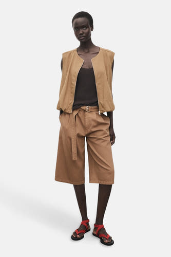 Bermuda marron de MANGO avec ceinture et sandales rouges.