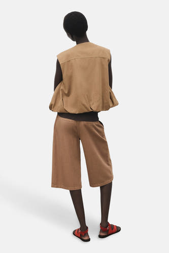 Shorts bruns de MANGO, vus de l'arrière, avec des jambes larges et des sandales rouges.