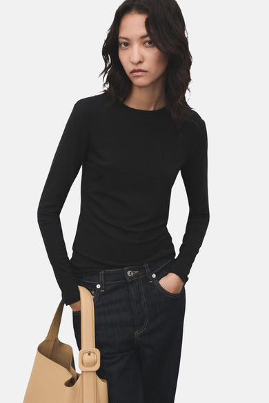 T-shirt noir à manches longues de MANGO, porté avec des jeans foncés et une poche main beige.