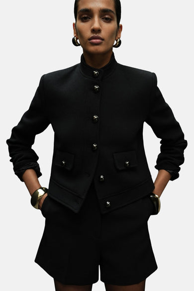 Blazer noir de MANGO, avec fermeture à boutons, longueur courte et poches brodées.