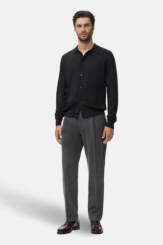 Gilet gris de MANGO porté sur un t-shirt sombre et des pantalons gris avec des chaussures marron.