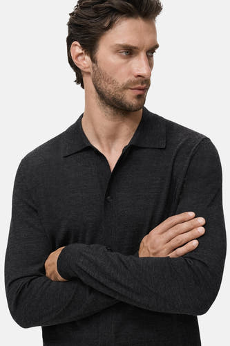 Gilet gris de MANGO, porté par un modèle avec les bras croisés et un regard sérieux.