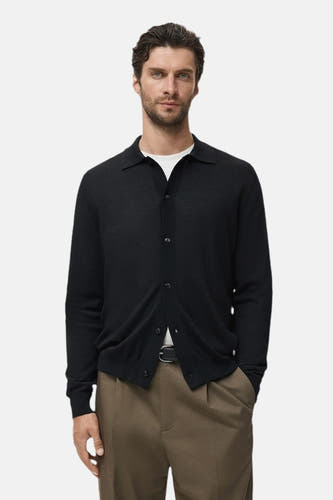 Gilet bleu de MANGO porté sur un T-shirt blanc, associé à des pantalons kaki et une ceinture noire.